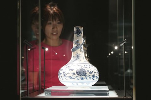◎ 觀眾欣賞明代天順五年(一四六一年)的青花螭龍纏枝牡丹紋瓶。在中國陶瓷史上,明代正統、景泰、天順三朝歷時廿九年,由於政局動盪混亂,御窑瓷器不落正規年款,令傳世品的斷代及深入研究舉步維艱。後人稱這個時期為「空白期」。這個青花瓶帶有「天順五年」字款,保存完好,帶款的天順年器物寥寥可數,是難得的珍品。它填補了「空白期」的空白,對探討明代三朝瓷器的發展甚具研究價值。(中新社記者張煒 攝)