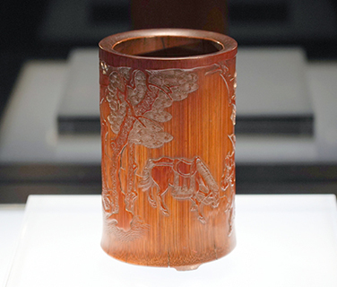 ◎ 清代吳之璠製作的淺浮雕丁山射雁圖筆筒。該筆筒以難度極高的「薄地陽文」技法刻成。古松、人物、馬匹造型精準,神氣動態活靈活現,留白得當,佈局緊凑。竹人吳之璠,字魯珍,活躍於康熙年間,在世時鮮為人知。直至一次偶然,乾隆在內府看到一件刻有「槎溪吳魯珍」的筆筒,才知道有這樣的一位民間高手,他的作品也從此為人所關注。(中新社記者張煒 攝)