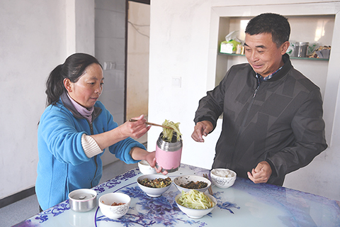 ◎ 十一月十三日早晨,楊月紅往保溫桶裡裝提前準備好的午餐。(新華社記者劉軍喜攝)