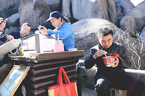 ◎ 十一月十三日,徐勝利(右一)送貨到達天池峰後,返回楊月紅工作的平台,與她一起吃午餐。(新華社記者張端攝)