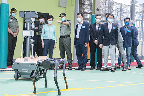 ◎ 五月二十二日,香港特區行政長官林鄭月娥在大潭峽懲教所主持懲教署「智慧監獄」開幕典禮。圖為行政長官林鄭月娥(左四)、保安局局長李家超(左六)及其他嘉賓聽取懲教署署長胡英明(左五)介紹即將引入使用的巡邏機械人和研發中的巡邏機械狗。(香港中通社)