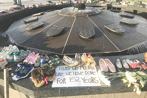 ◎ 圖為五月三十日,在加拿大渥太華的議會廣場,參加悼念活動的人們擺放鮮花、鞋子等物品。(新華社)