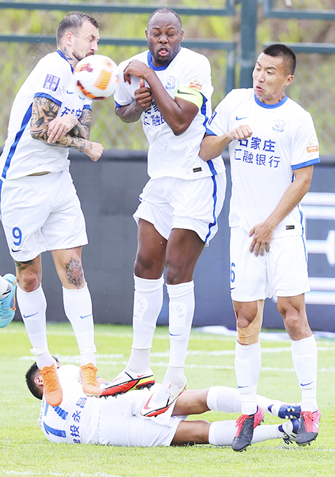 ◎ 六月九日,廣東省梅州市五華橫陂足球小鎮,滄州雄獅隊(白衣)一比一戰平梅州客家隊。圖為滄州雄獅隊隊員躍起防守。(中新社發 劉佔崑 攝)