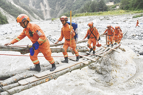 ◎ 九月六日,四川甘孜州瀘定縣磨西鎮,甘孜州森林消防支隊康定中隊隊員通過簡易木橋,深入山區開展救災工作。九月五日,四川瀘定發生六點八級地震。(中新社記者張浪攝)