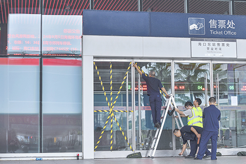 ◎ 九月五日,海南海口,海口東站的工作人員加固玻璃門,為防禦颱風做準備。當日,海南省政府提升颱風二級預警為颱風一級預警,今年第十一號颱風「摩羯」(超強颱風級)預計將於九月六日下午到夜間在海南瓊海到廣東電白一帶沿海登陸。受颱風「摩羯」影響,九月五日十八時起海南環島高鐵、海口市域列車全線停運。(中新社記者駱雲飛 攝)