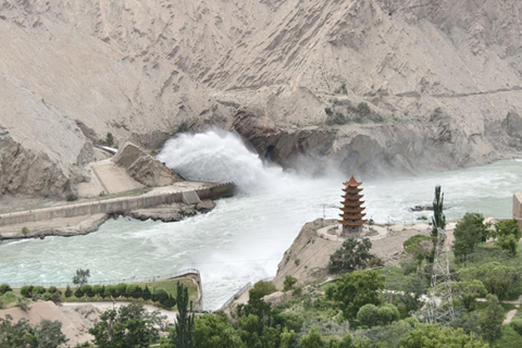 8月6日,洩洪中的烏魯瓦提水庫。裸色山體與岸上綠植交相呼應,吸引人們駐足。(中新社記者 李夢 攝)