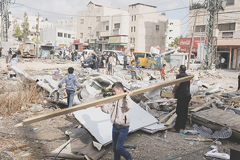 ◎ 十月十九日,以色列在約旦河西岸城鎮圖巴斯發動軍事行動後,巴勒斯坦人站在被摧毀的道路旁。(美聯社圖片/Majdi Mohammed)
