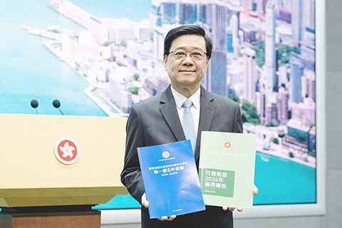 ◎ 九月十五日,香港特區行政長官李家超出席行政會議前表示,香港首個五年規劃採用藍色封面,寓意藍天、開放、進步和穩重;施政報告則沿用綠色,象徵政策延續、活力和希望。特區政府製作一套兩冊摘要,輯錄兩份文件重點,封面以晨光下的維港為主題,並融合藍綠兩種主色,方便市民掌握主要內容。圖為香港特區行政長官李家超展示「行政長官二0二六施政報告」與「香港第一個五年規劃」封面。(香港中通社記者 陳奕啟 攝)